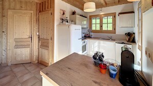 Una cocina con vigas de madera, un refrigerador, un lavamanos y una ventana.