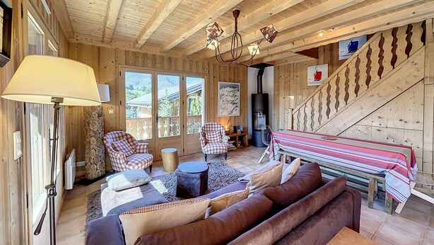 Un interior acogedor de madera con un sofá, sillas, una mesa y una chimenea.