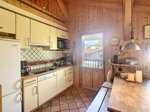 Une cuisine de taille réduite avec des murs en bois, un pare-feu en carrelage et des appareils électroménagers de base.