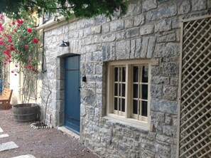 A stone building with a blue door and a window with white shutters.