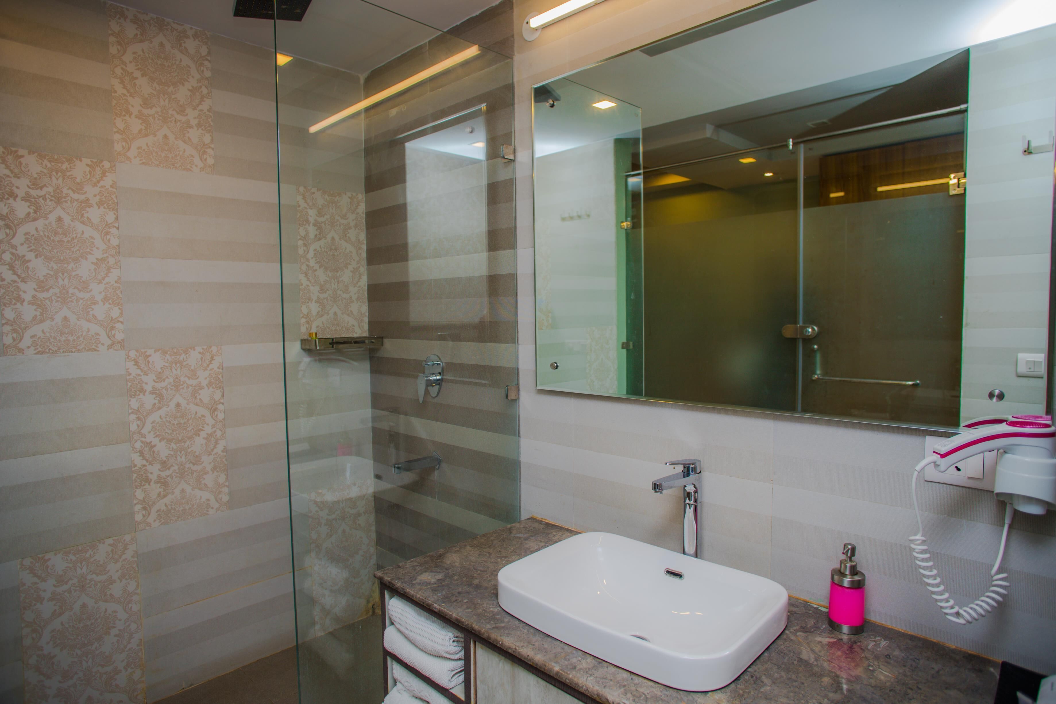 A modern bathroom with a glass shower enclosure, a white sink, and a large mirror above it.