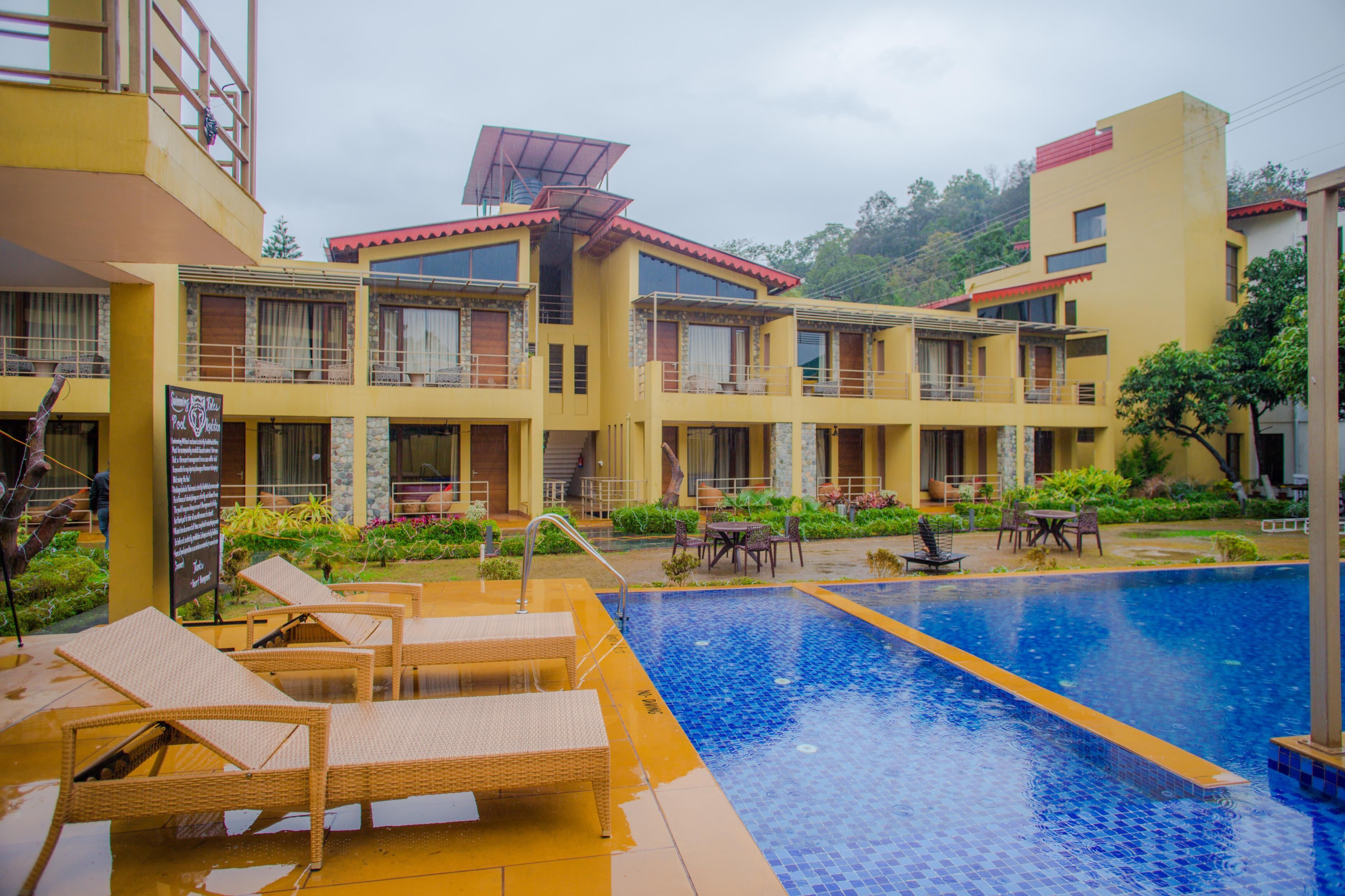 A hotel with a swimming pool, outdoor seating, and a garden area.
