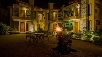 A two-story building with a fire feature in the courtyard, outdoor seating, and a well-lit entrance.