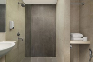 A bathroom with a sink, a shower, and a towel rack.