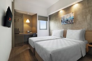 A hotel room with two beds, a desk, a chair, a TV, and a painting on the wall.