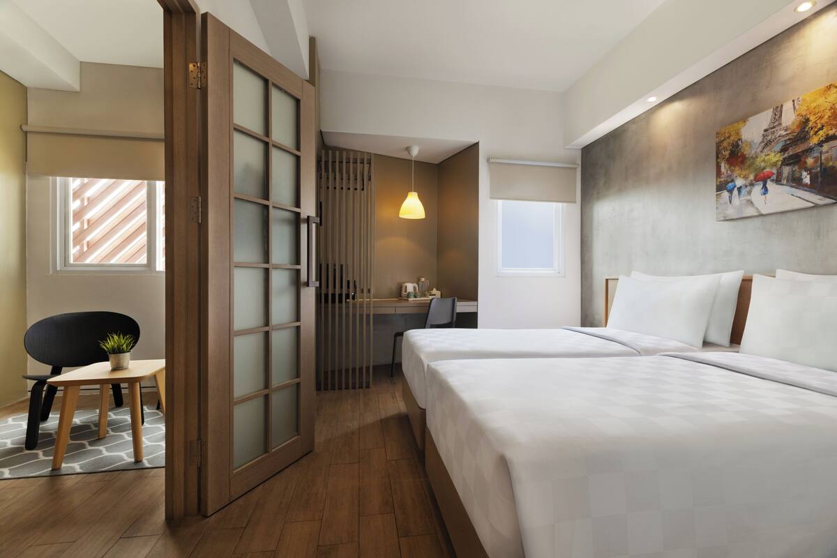 Ein Hotelzimmer mit Bett, Schreibtisch, Stuhl und Fenster.