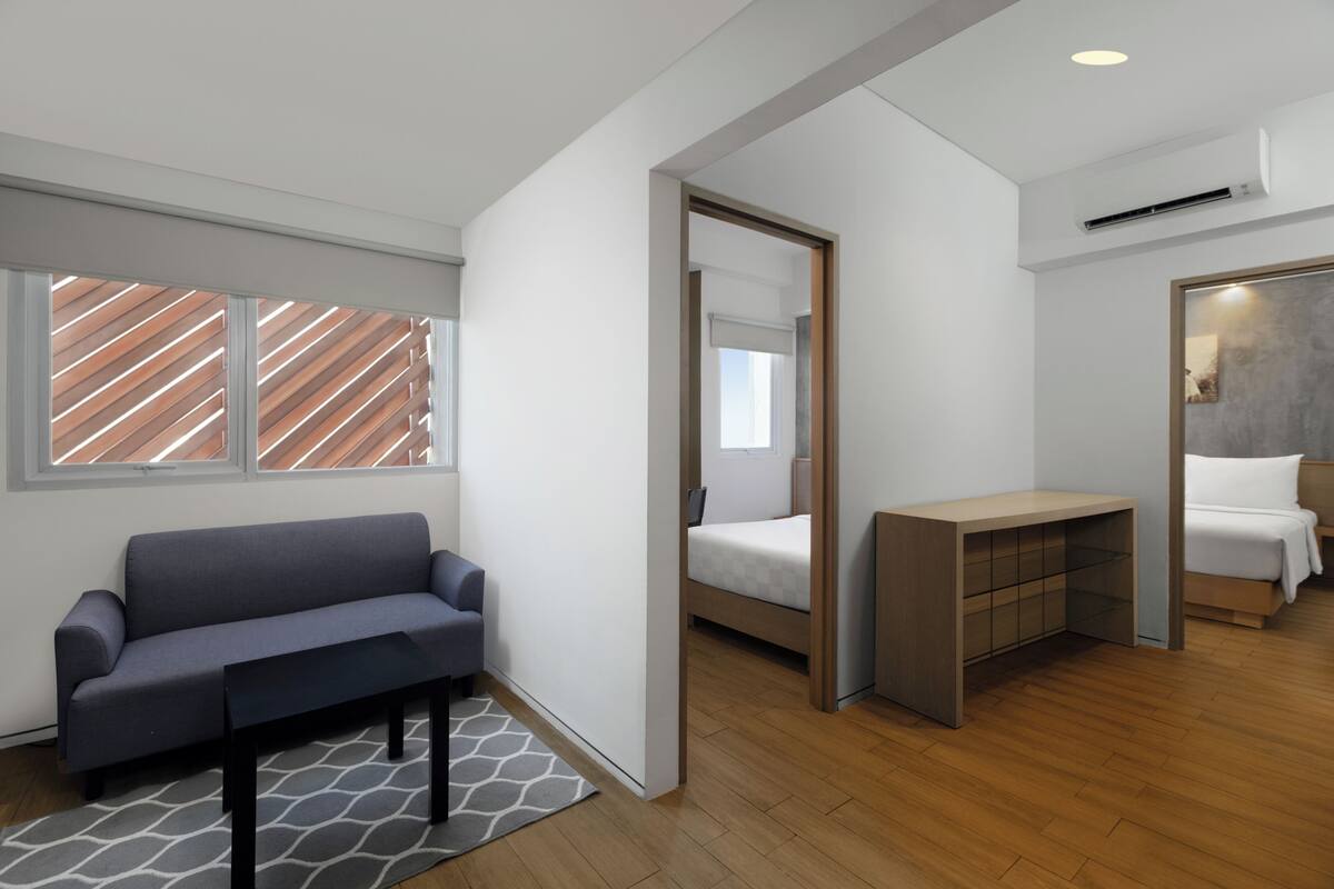 Ein modernes Zimmer mit einer Couch, einem Bett, einem Schreibtisch und einem Spiegel.