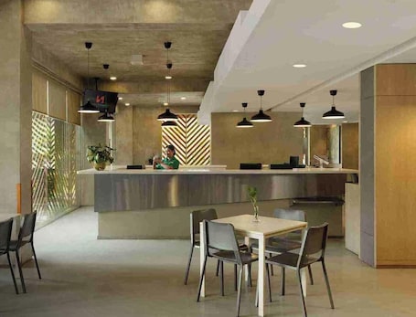 A modern hotel lobby with a reception desk, seating area, and decorative wall patterns.. Swiss-Belexpress Cilegon
