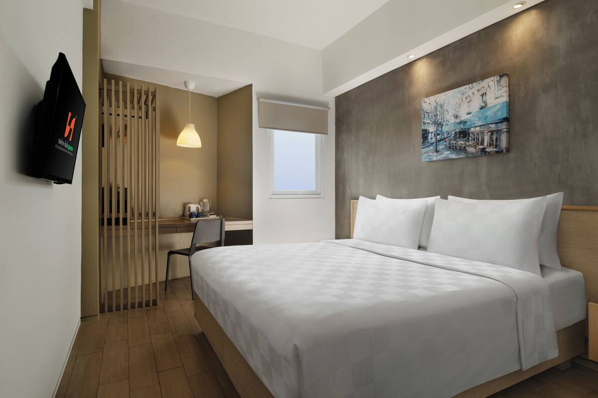 Ein modernes Hotelzimmer mit Bett, Schreibtisch, Stuhl und einem Bild an der Wand.