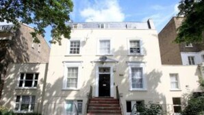 A two-story building with a central entrance, a small porch, and a staircase leading to the door. - 2-bed, Sleeps 4, Garden (London)