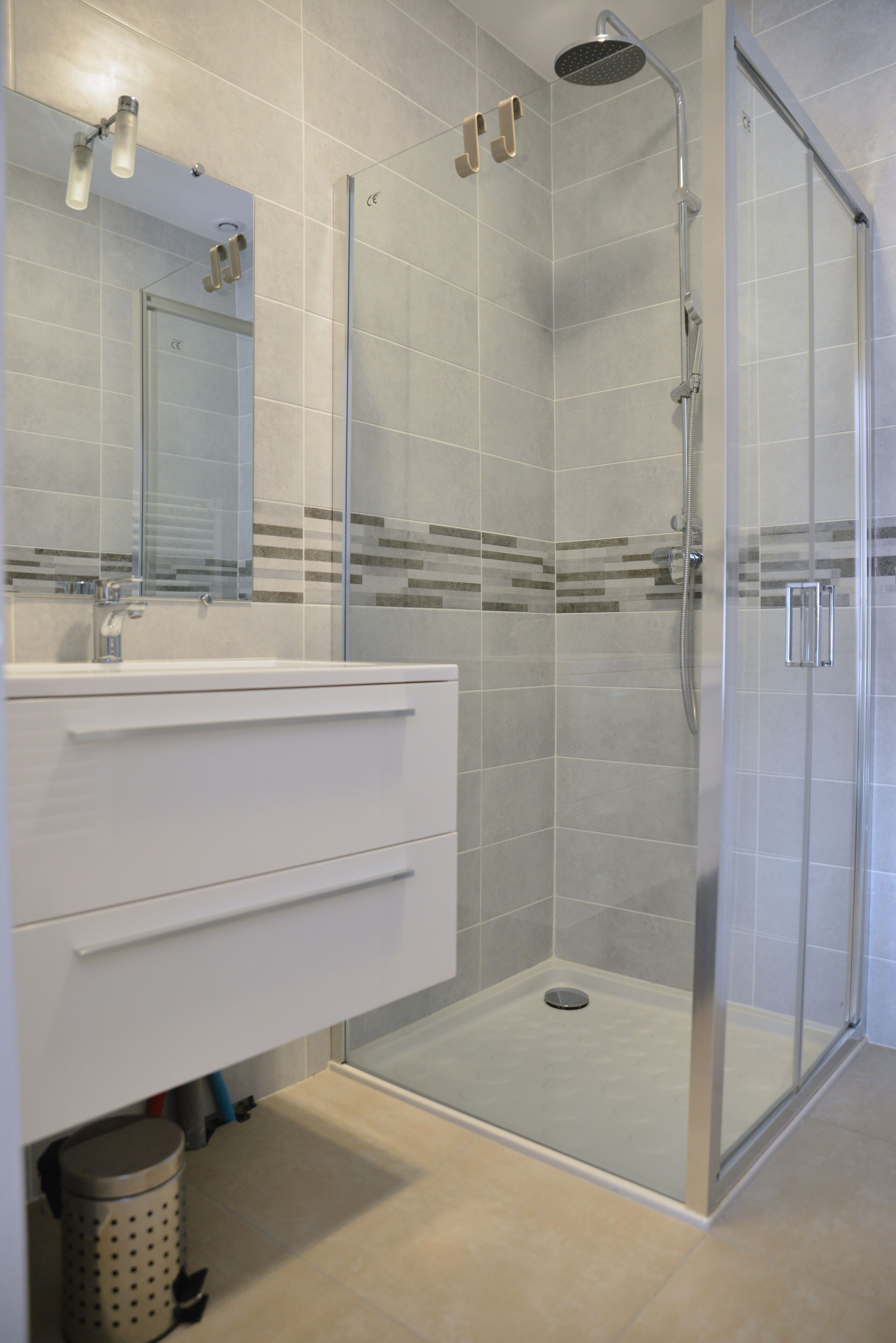 A modern bathroom with a glass-enclosed shower, a white vanity with drawers, and a tiled backsplash.