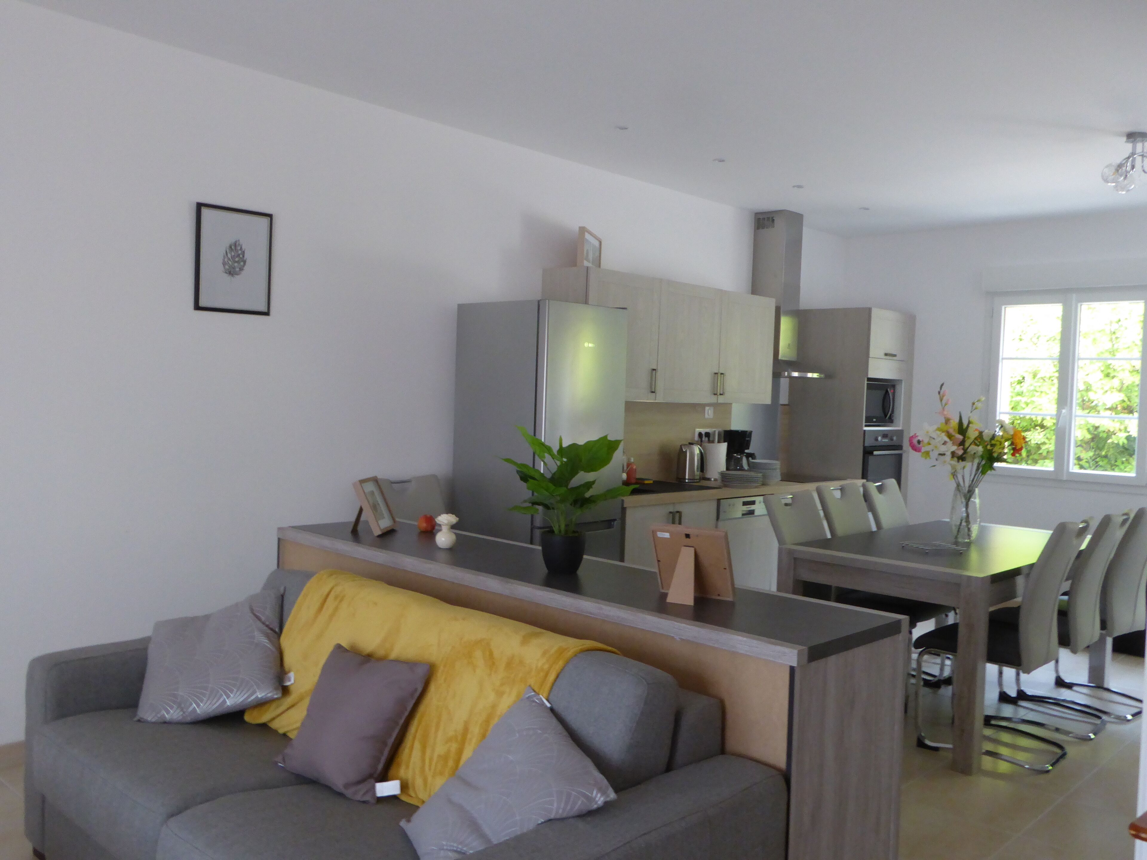 Un salon moderne avec un canapé gris, une table basse et un coin repas comprenant une table et des chaises.
