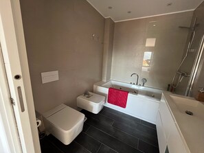 Bathroom features a white toilet, sink, bathtub, and shower area.