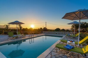 A swimming pool with lounge chairs and umbrellas, surrounded by stone walls and vegetation. - Villa Helios, luxury holiday home, private pool, peaceful rural environment (Xirosterni, Crete)