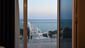 Un balcón con puertas de vidrio transparente y vistas al mar.