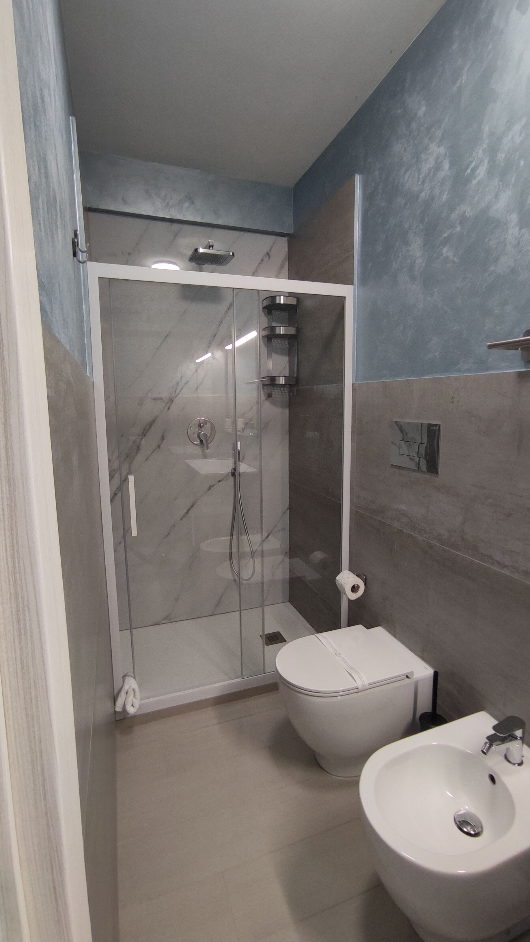 Un bagno moderno con doccia vetro, water e lavandino.