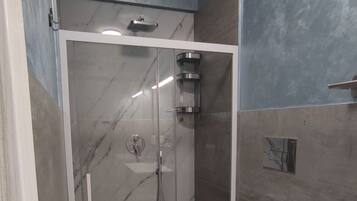 Un bagno moderno con doccia vetro, water e lavandino.