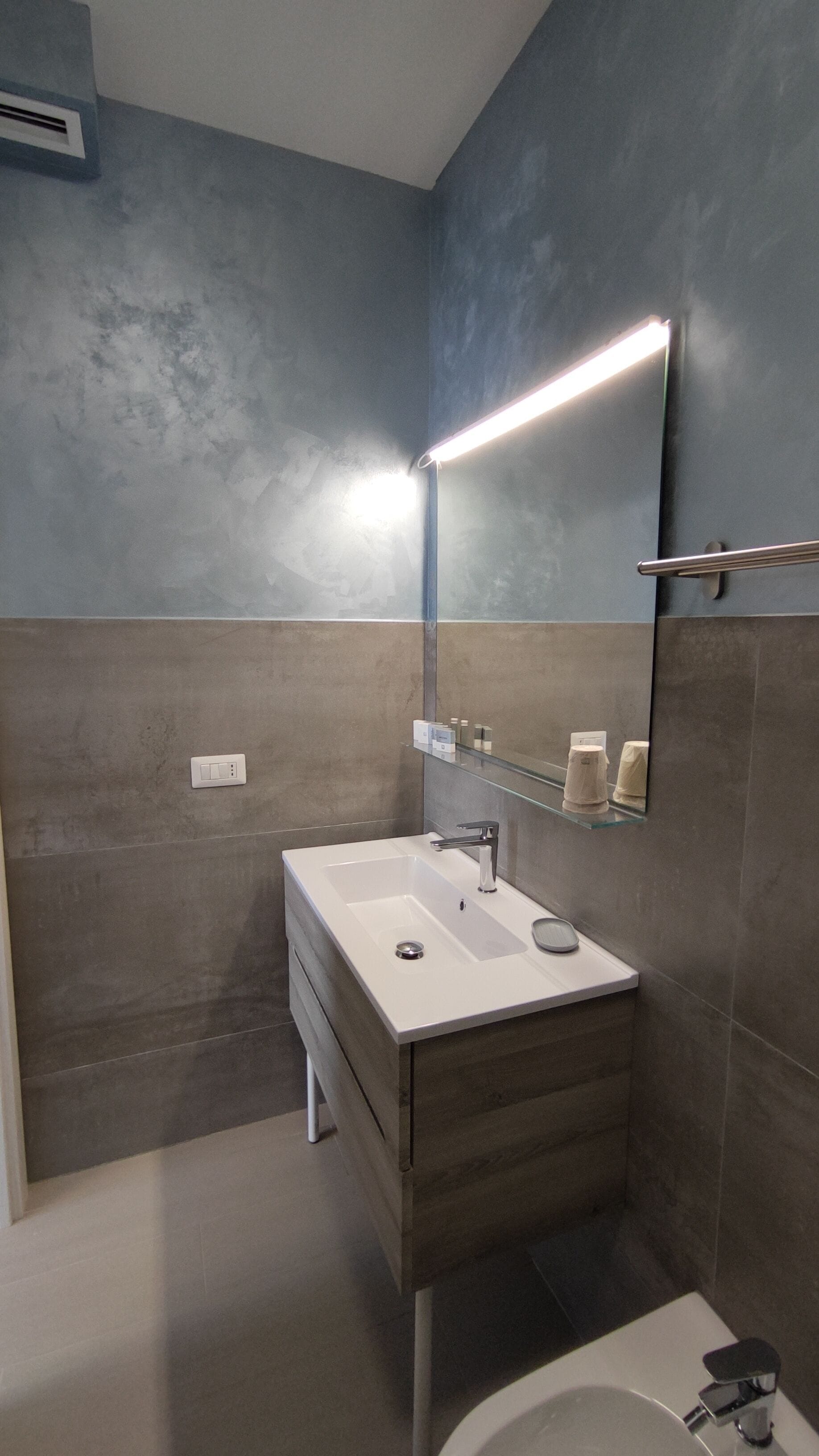 Une salle de bain moderne avec un lavabo blanc, un miroir et des toilettes.