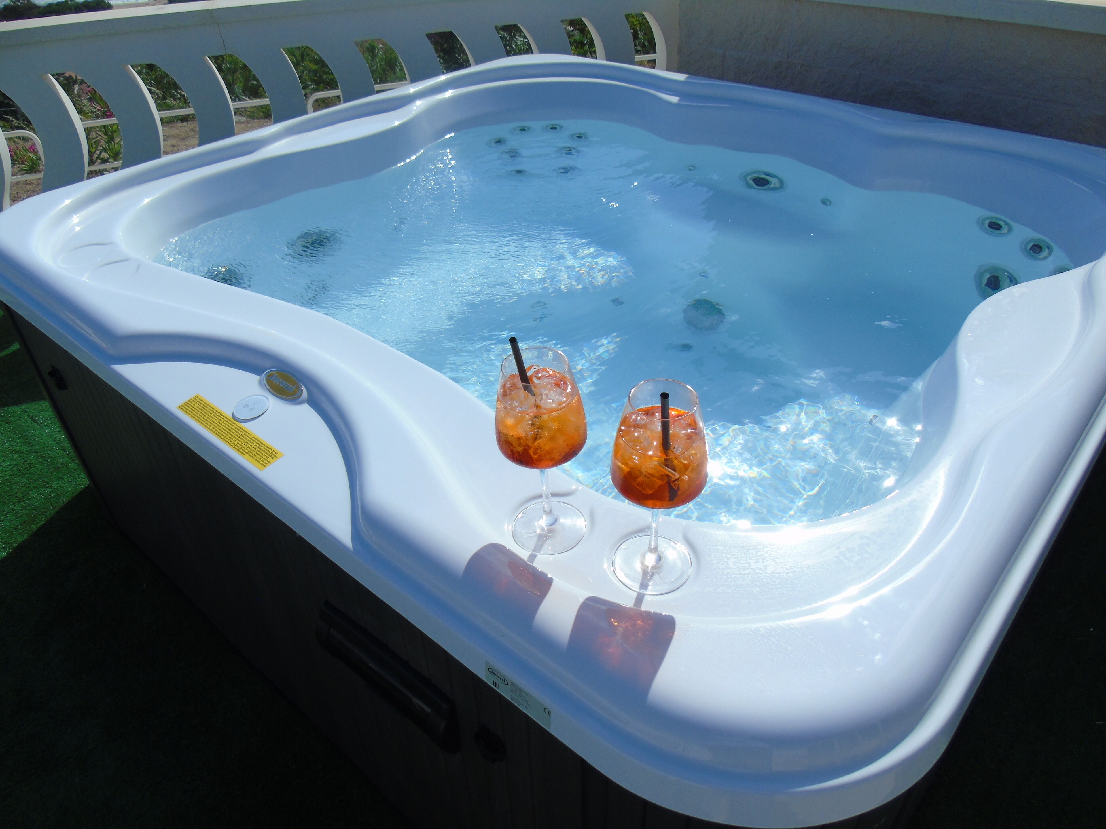 A hot tub with two glasses of iced drinks on the side.