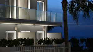 Un edificio moderno de dos pisos con balcones, ventanas amplias y una palmera.