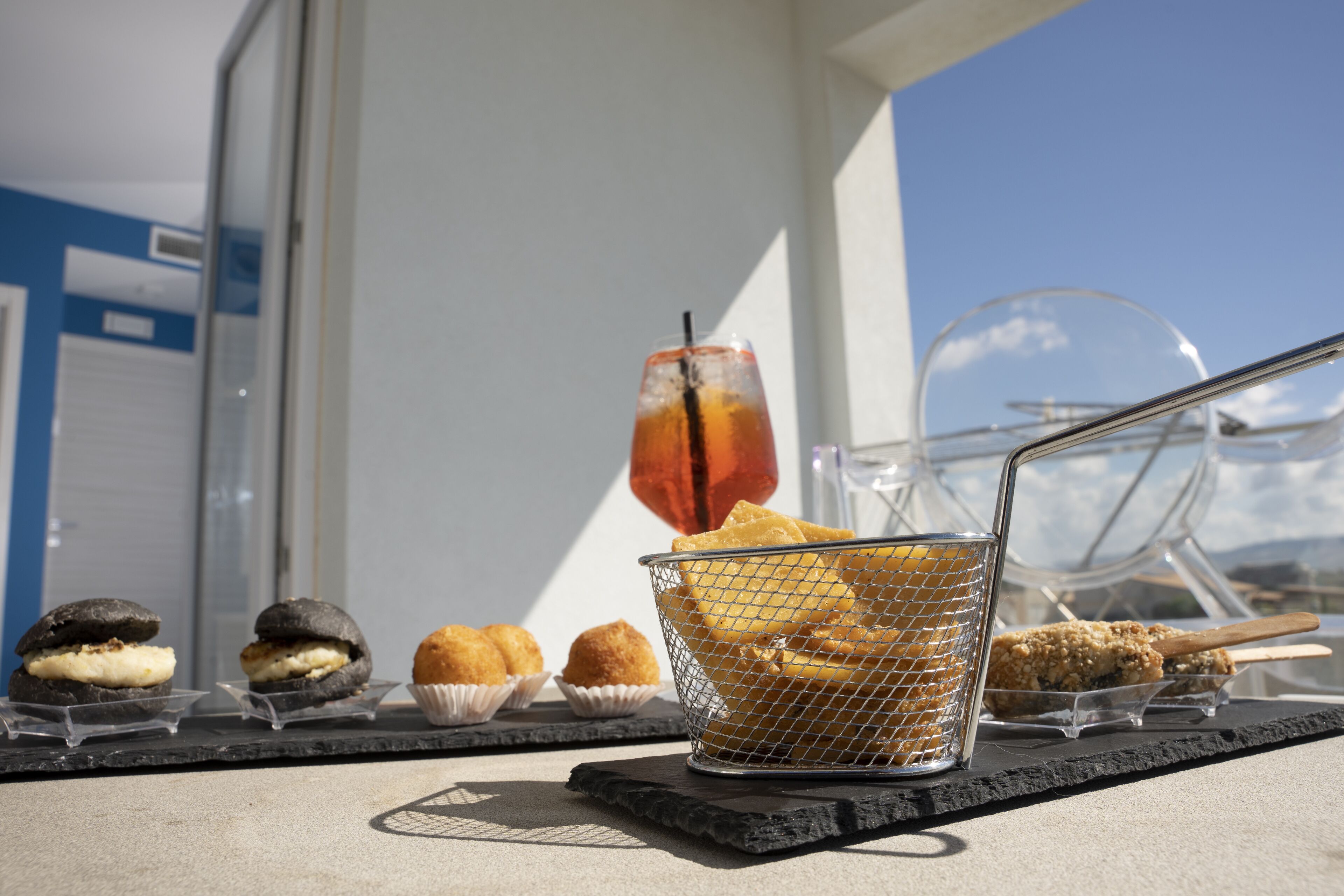 A selection of desserts on a table, including a drink in a glass with a straw, a basket of pastries, and various other baked goods.