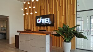 A hotel reception desk with a wooden backdrop and a large TV screen displaying the hotel name. - Otel Hotel Sibu (Sibu)