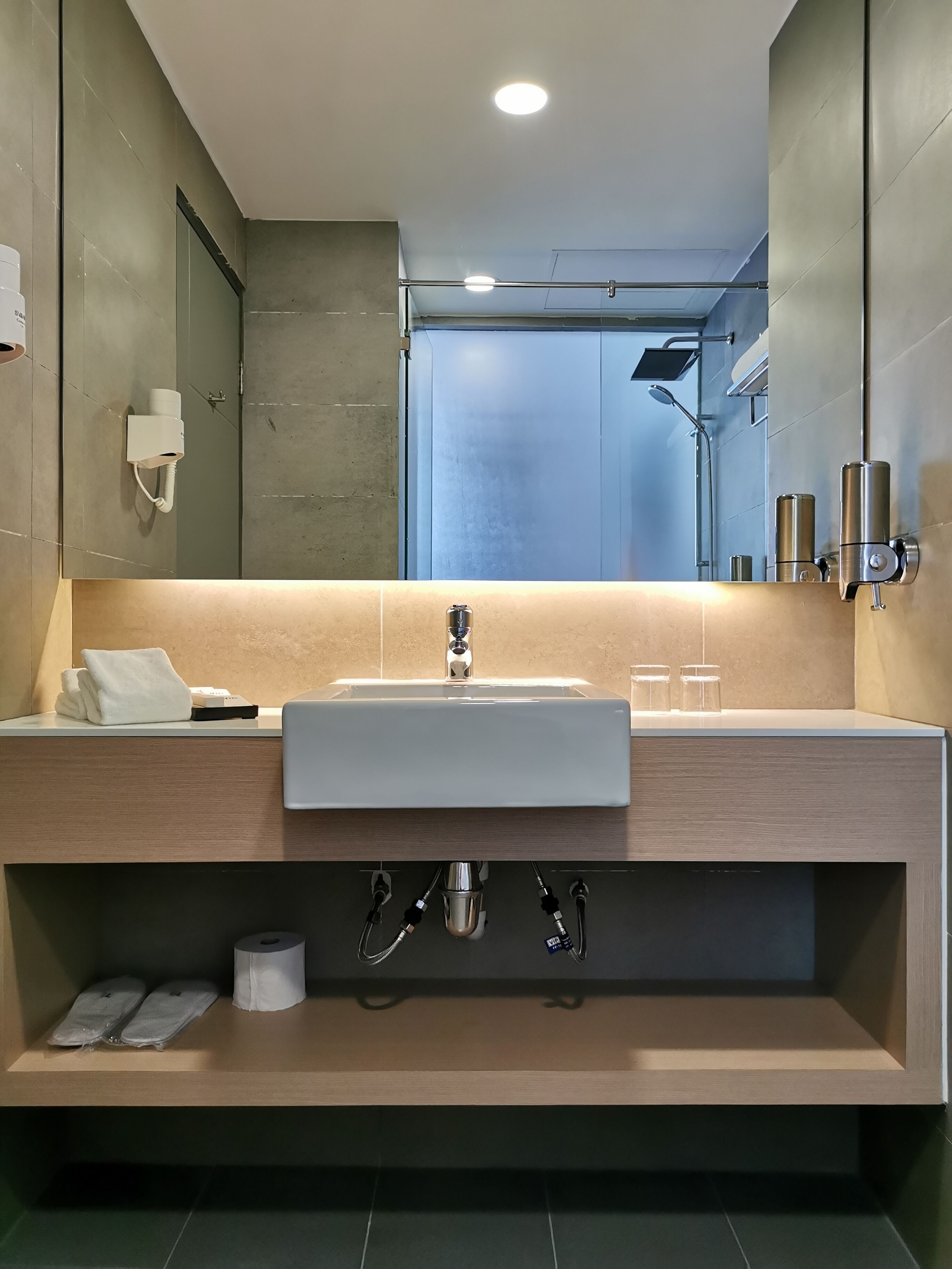 A modern bathroom with a large mirror, a sink, and a shower.