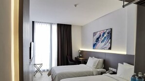 A hotel room with two beds, a desk, a chair, a TV, and a painting on the wall. - Otel Hotel Sibu (Sibu)