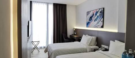 A hotel room with two beds, a desk, a chair, a TV, and a painting on the wall.