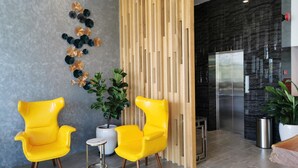 A modern interior with two yellow chairs, a potted plant, a decorative wall, and a refrigerator. - Otel Hotel Sibu (Sibu)