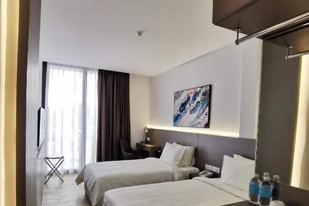 Ein Hotelzimmer mit zwei Betten, einem Schreibtisch, einem Stuhl, einem kleinen Tisch, einem Spiegel und einem Bild an der Wand.