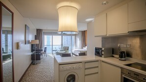 Quarto de hotel compacto com cozinha compacta, máquina de lavar, área de refeições e vista para a paisagem urbana.