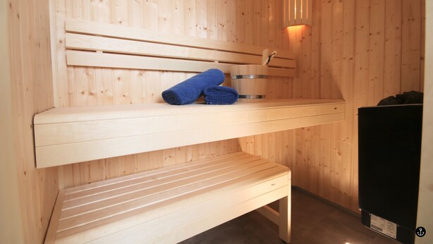 A wooden sauna with benches and a towel on one of them. - Refugium 4 (Kellenhusen)