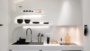 Una cocina moderna con muebles blancos, un lavamanos negro y un horno empotrado.