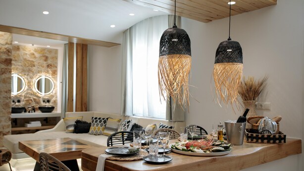 Un comedor moderno con una isla de madera, dos lámparas colgantes y una pared decorativa de piedra.