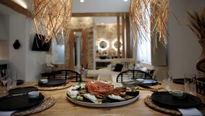 Una mesa de comedor dispuesta con platos, vasos y una langosta como centro de mesa.