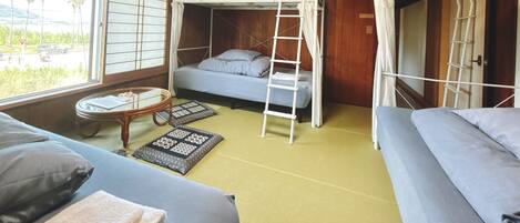 Une chambre avec un lit superposé, une fenêtre, une petite table et un canapé.