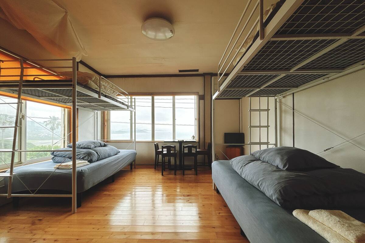 A dormitory room with bunk beds, a sofa, a desk, and a television.