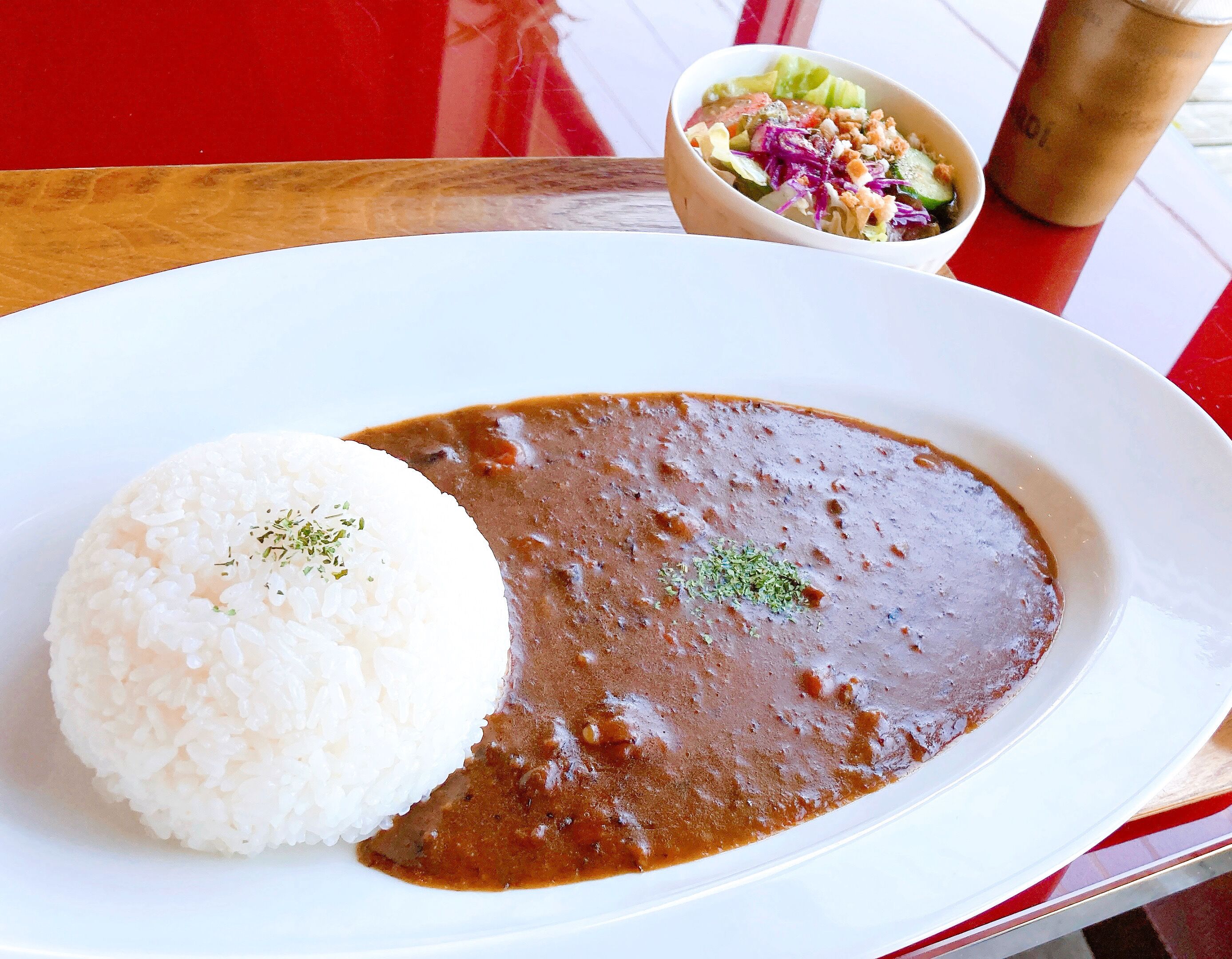 A plate of white rice and a brown sauce, possibly a stew, on a white plate.