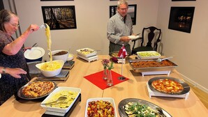 Een buffet met diverse gerechten, waaronder pasta, salades en pizza.