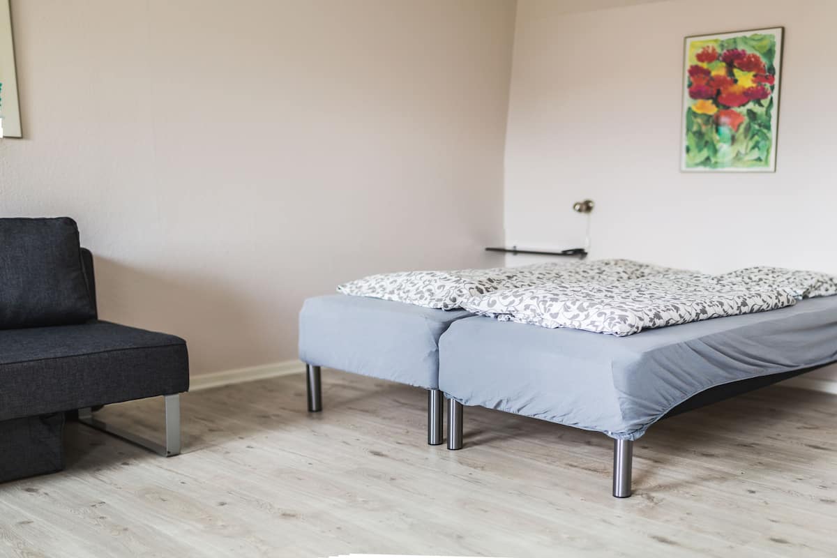 Een kamer met een bed, een bank en een schilderij aan de wand.