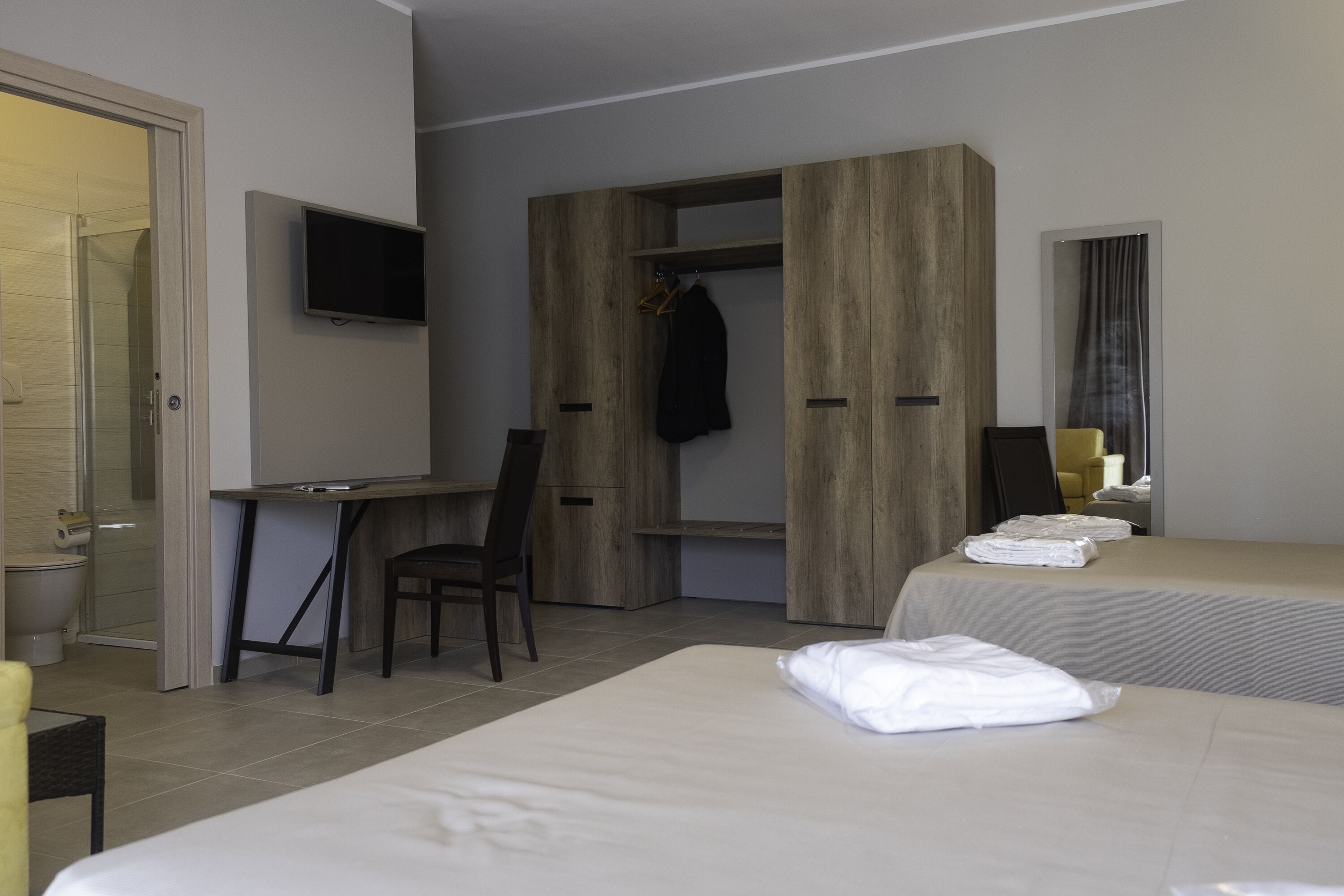 Une chambre d’hôtel équipée d’un lit, d’un bureau, d’une chaise, d’une télévision et d’une armoire.