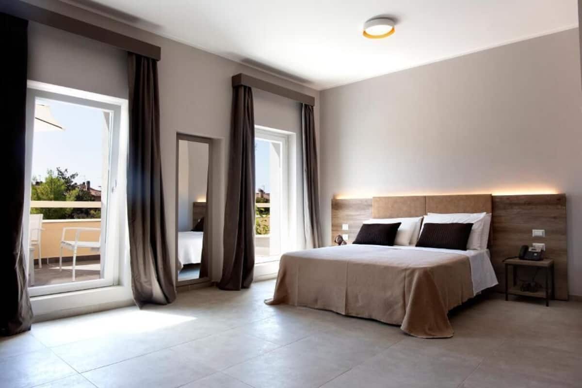 Une chambre moderne avec un grand lit, une table de chevet, une commode et une vue sur l’extérieur grâce à une porte coulissante.