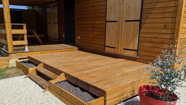 Una terraza de madera con un banco integrado y una planta en maceta.