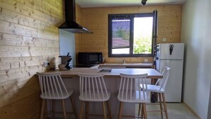 Una cocina compacta con paredes de madera, una isla central con taburetes, microondas, fregadero y refrigerador.