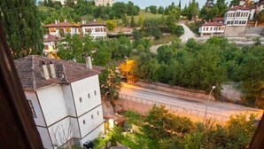 A view from a balcony overlooking a residential area with houses, a grassy lawn, and a paved road. - Kurkcu Konak (Safranbolu)
