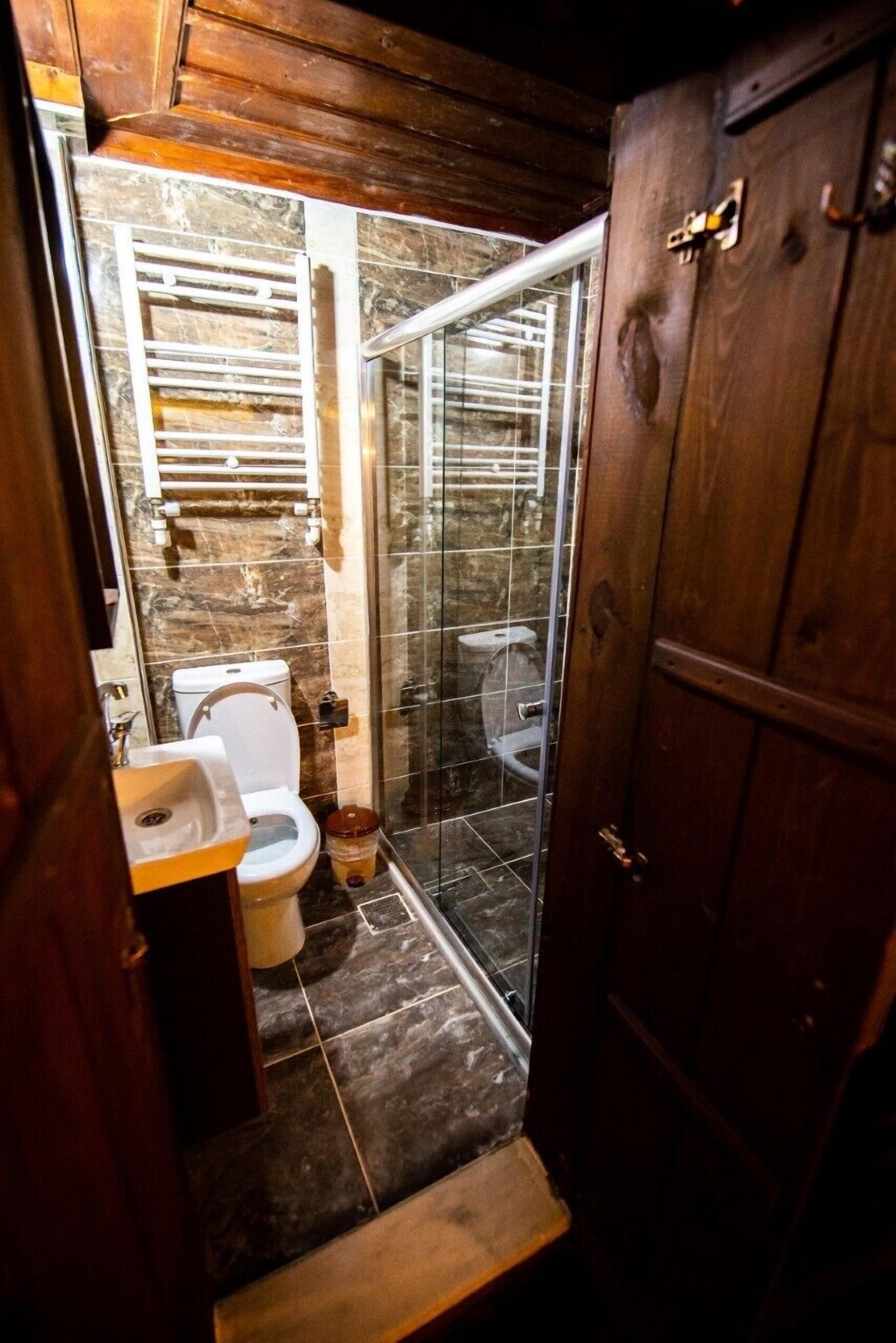 A compact bathroom with a toilet, sink, and glass shower enclosure.