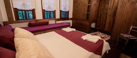 Una habitación con una cama grande, una banca y un armario.