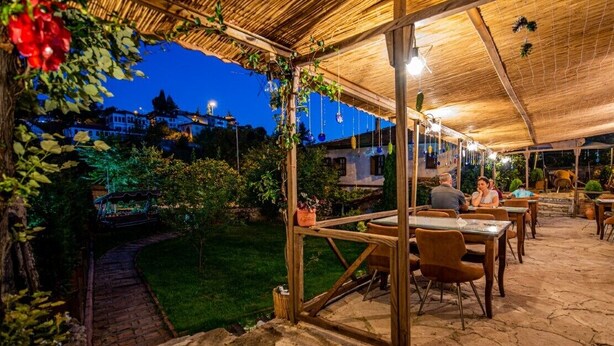 An outdoor patio with stone flooring and wooden tables and chairs. - Kurkcu Konak (Safranbolu)