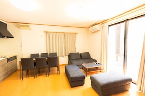 Relax in this spacious living room with a dining area, sofa, and kitchen.